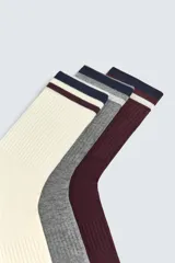 Pack de tres pares de calcetines de tejido acanalado (rib), con banda de color en el borde superior. Incluye un par color crema, uno gris jaspeado y uno bordó oscuro.
