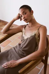 Top de tirantes fino color marrón topo, con detalles de encaje beige en el escote en V y en los laterales. Presenta un diseño fluido y ligero.