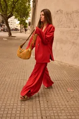 Cartera tipo baguette de gamuza color chocolate, con diseño decorado con diversos apliques metálicos, perlas y piezas de piedra. Cuenta con cierre superior y correa ajustable.