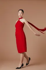 Vestido midi de crepe elastizado color rojo, con escote halter, detalle metálico en el cuello y lazo largo que cae desde el hombro. Diseño ajustado al cuerpo con frunces laterales.