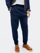 Pantalón deportivo tipo babucha de color azul marino, con cintura elástica ajustable mediante cordón y puños acanalados en los tobillos.