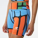 Calza corta de lycra con estampado geométrico en tonos naranja, celeste y verde. Logo de New Balance estampado en la pierna derecha.