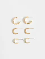 Set de tres pares de aros dorados tipo argolla de diferentes tamaños, uno con detalle de corazones rosados.