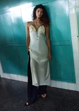 Vestido midi de tejido satinado en color beige claro, con escote halter en pico, detalles fruncidos en el pecho, tirantes finos y abertura lateral.