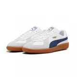 Championes Puma modelo Army Trainer, de diseño retro en color blanco con detalles en verde oscuro y suela de goma color caramelo. Presenta refuerzos de gamuza en la puntera y el logo de la marca en dorado en el lateral.