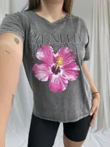 Remera gris de corte clásico con estampa de flor de hibisco fucsia y texto en gris.