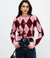 Cardigan corto de punto con estampado de rombos en tonos rosado y bordó, cuello redondo, mangas largas y cierre frontal con botones revestidos.