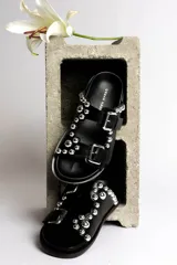 Sandalias marrones de cuero con doble tira, hebillas plateadas y apliques de tachas redondas plateadas.