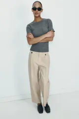 Pantalón de tiro alto con corte recto, bolsillos delanteros y detalle de pinzas con botones en la cintura. Cuenta con cierre frontal de cremallera y gancho metálico.