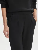 Pantalón negro de tejido DoubleSoft, corte ajustado con puños enrollados, pinzas delanteras y traseras, y bolsillos con forma.