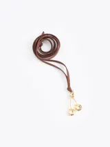 Choker de cordón largo de cuero sintético con dije metálico en forma de cerezas doradas.
