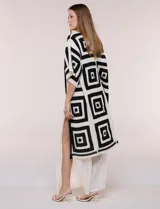 Cardigan largo confeccionado en tejido de punto calado estilo crochet, de color amarillo y blanco, con diseño geométrico de cuadrados, mangas amplias tipo kimono y corte abierto al frente.