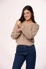 Buzo tejido de punto con textura tipo waffle, color beige, con escote en V y mangas largas con puños ajustados.