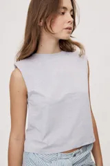 Remera sin mangas negra con cuello redondo y hombros estructurados con hombreras, de corte recto y largo a la cintura.