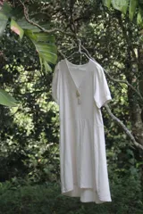 Vestido corto color blanco hueso, de lino con mezcla, corte evasé, cuello en V y botones de nácar.