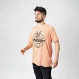 Remera de manga corta color salmón con estampa circular en el frente que incluye un águila, la bandera de Estados Unidos y el logo de Wrangler.