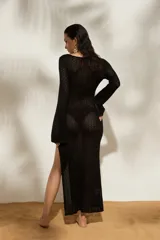 Vestido largo de tejido de punto blanco, con escote profundo en V, detalle de argolla frontal, mangas largas y tajo lateral en la falda.