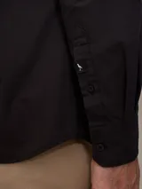 Camisa negra de algodón de manga larga, con cuello clásico y cierre frontal con botones.