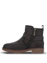 Bota corta de descarne color gris, con diseño de caña baja y detalle de tira con hebilla metálica lateral. Cuenta con suela de goma texturizada y cierre lateral para un ajuste cómodo.