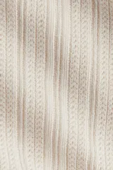 Top ajustado de punto acanalado suave, color beige, con cuello alto y mangas largas acampanadas.