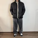 Campera puffer color gris claro, con cuello alto y cierre frontal con cremallera.