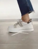 Sneakers de mujer estilo deportivo y urbano, color negro con detalles en beige claro. Presentan puntera y talón en negro, cuerpo principal en negro, y estrella lateral, cordones y tira de velcro en beige claro. La suela es blanca y el interior negro con la inscripción "LUCY IN THE SKY".