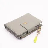 Billetera gris con cierre de broche y cierre de cremallera, con adorno de borla de colores.