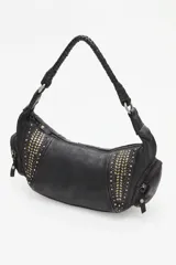 Cartera de cuero vacuno negra, estilo media luna o hobo, con asa de hombro trenzada. Presenta paneles laterales decorados con tachas metálicas doradas y plateadas. Cuenta con bolsillos externos con cierre en los laterales.