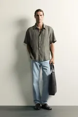 Jeans regular fit de mezclilla negra con efecto lavado, corte recto y tiro medio. Cuenta con diseño de cinco bolsillos y cierre frontal con cremallera y botón.