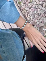 Pulsera rígida de alpaca con diseño abierto ajustable, decorada con cuatro piedras de nácar engarzadas en línea.