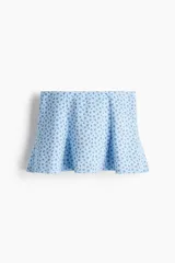Short pollera mini de tejido suave efecto neopreno, color celeste con pequeño estampado de flores oscuras, diseño ajustado con vuelo y nesgas.