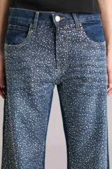Pantalón de jean de tiro medio y corte wide leg, color azul denim, con apliques de strass plateados simulando una lluvia de brillantes. Confeccionado en tejido denim 100% algodón.