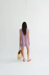 Vestido corto sin mangas en color rosado con estampado floral en blanco y negro. Presenta una cartera de botones asimétrica en el frente y detalle de volado fruncido en el ruedo. Confeccionado en algodón liviano.