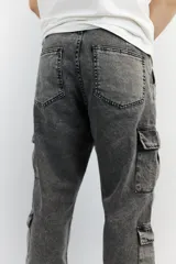 Pantalón jean cargo gris nevado con doble bolsillo externo en cada pierna.