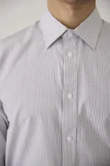 Camisa de vestir blanca de manga larga, con cuello clásico y cierre frontal de botones. Presenta un corte entallado que se adapta a la silueta.