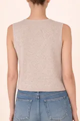 Chaleco de punto color beige, con cuello redondo y cierre frontal de botones con detalle de perlas.