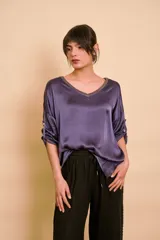Blusa holgada de satén color beige, con escote en V y mangas largas con trabilla para sujetar remangadas.