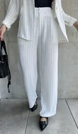 Pantalón blanco con finas rayas verticales negras, de corte palazzo y tiro alto.