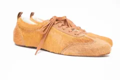 Championes de cuero color tostado con acabado de pelo sintético, diseño de cordones y suela plana.