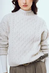 Sweater tejido negro de silueta relajada, con cuello alto y textura trenzada.