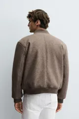 Cazadora bomber marrón con interior efecto pelo, cuello y puños de rib elástico, bolsillos de vivo en cadera, bolsillo interior y cierre frontal con cremallera.