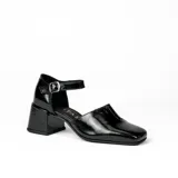 Zapato de cuero vacuno color gris topo, con talón descubierto y pulsera con hebilla. Tiene taco de madera forrado en cuero y suela de goma. La horma es de punta cuadrada, ancha y cómoda.