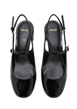 Zapato destalonado de tacón bloque bajo, con acabado efecto charol, puntera redondeada y cierre de hebilla ajustable.