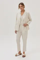 Chaleco sastrero color beige de lino y viscosa metalizado, con cuello en V y cierre con botones.