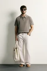 Remera polo regular fit de color gris oscuro, confeccionada en tejido de algodón con textura de rayas verticales. Cuenta con cuello solapa, cierre frontal con botones y mangas cortas con terminación en rib.