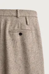 Pantalón relaxed fit de hombre color marrón con textura estructurada, cintura con pliegues frontales, bolsillos laterales y cierre frontal con cremallera y botón.