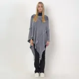 Poncho de tejido de punto gris con diseño asimétrico, detalles de flecos en los bordes y costuras decorativas con textura desflecada.