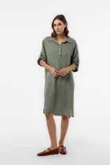 Vestido camisero midi de lino color verde militar, con calce relajado, cuello clásico, cierre frontal con botones parciales, mangas regulables con presilla y bolsillos delanteros amplios.