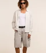 Bermuda de hombre en denim de algodón, modelo cargo, corte baggy y tiro medio. Presenta bolsillos laterales tipo cargo y cierre tradicional con botón y cremallera.