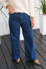 Jean de tiro medio en color azul oscuro, con costura vertical decorativa en el centro de cada pierna y cierre frontal con botón metálico.